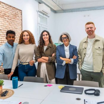 Group of multi ethnic business people posing together in a bright, contemporary office space, symbolizing teamwork, collaboration, and professional success